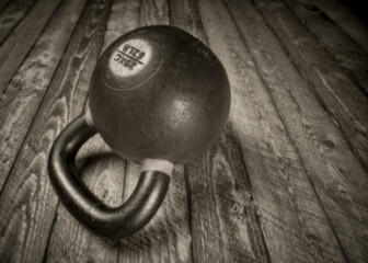 Naklejka na ściany i meble heavy iron kettlebell on a rustic wood background - fitness concept, soft focus black and white image shot with lensless pinhole camera