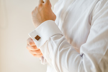 Man putting on a white shirt and cufflinks.  Preparation. Formal wear. 