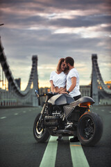 Love and romantic concept. Beautiful couple on motorcycle stands opposite each other in the middle of the road on the bridge, on double solid