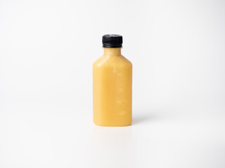 orange pastel color drink in plastic bottle container with empty logo label. mixed many vegetables and fruits smoothie juice on studio background.