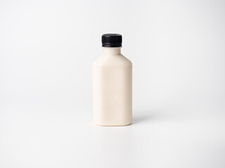white pastel color drink in plastic bottle container with empty logo label. mixed many vegetables and fruits smoothie juice on studio background.