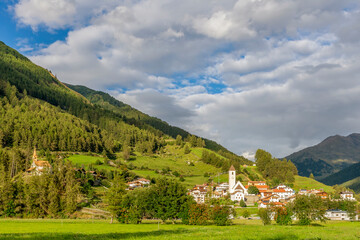 Fototapeta na wymiar The mountain village of Curon (Graun) in Val Venosta, against a beautiful sky, on a sunny summer day, South Tyrol, Italy