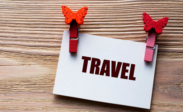 TRAVEL - word on a white sheet with beautiful clothespins on a wooden background
