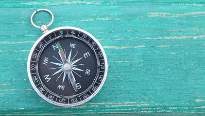 Classic round compass on green wooden vintage background as symbol of tourism with compass, travel...