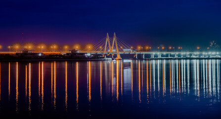 Obraz premium Millenium bridge in Kazan, reflected in the waters of the river Kazanka. Cable-stayed bridge across the river. The bridge with night lighting.
