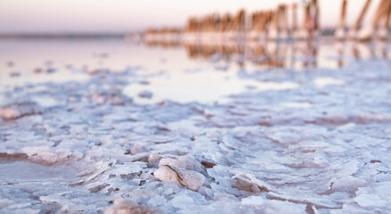 Unique salt lake Kuyalnik in Ukraine. Wooden poles reflected on the surface with the salt crystals. 