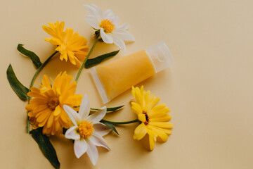 Cosmetic bottle container with flowers on yellow background.