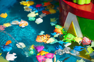 Fototapeta na wymiar Toy plastic fish in blue water.Toy fishing