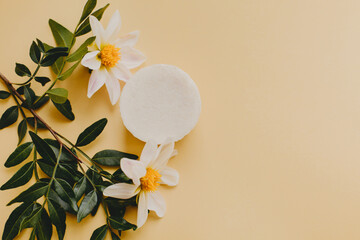Cosmetic soap with flowers on yellow background.