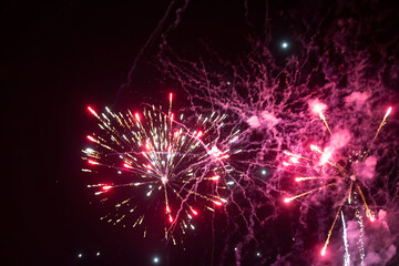 Fototapeta na wymiar Pink spots of fireworks on a black background. Festive background.