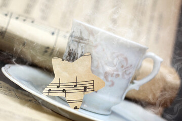 A white cup of coffee with steam and a star musical note