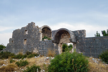 Fototapeta premium Damaged walls of church in ancient city Korikos, Kızkalesi, Turkey. Altar part of building is on background. City was important port of medieval Kingdom of Cilicia, abandoned after series of wars