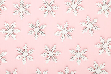 Christmas background. White snow decorations on a pink background.