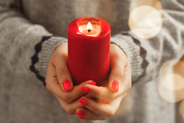 Red burning Christmas candle in female hands