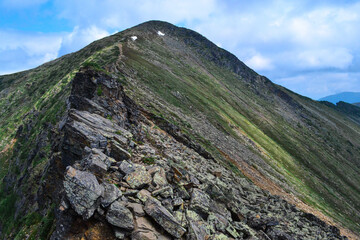 Obraz premium Hamar-Daban, stone rock with colored moss on a sharp ridge in the Baikal green mountains, Siberia, Chersky peak