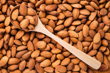 Top view of fresh raw peeled almonds nut in spoon and background.