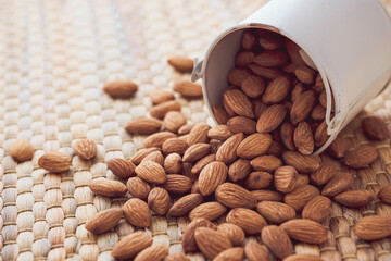 Closeup of brown fresh almonds seed in white cup on Water hyacinth placemats.