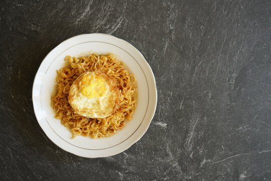 stock photo tasty fried noodle with fried egg on a white plate and a stone pad