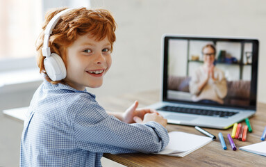 Fototapeta Cheerful boy during online lesson at home. obraz