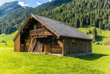 The path leading to the Sämtisersee lake in a late summer afternoon among old wooden stables and cottages in Appenzell