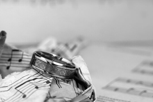 Gold wide ring and paper musical notes, black and white image