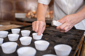 Unrecognizable baker woman putting cupcake molds