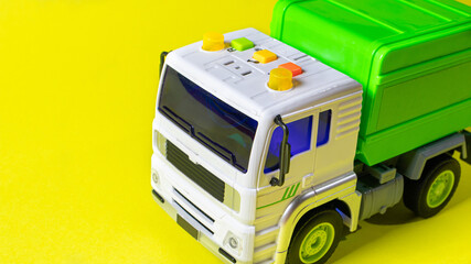 Naklejka premium The toy garbage truck white-green with a yellow background. Children's toy car with buttons.