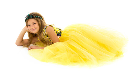 A little girl is lying on the floor. Studio photo session on a white background.