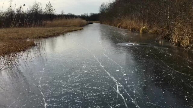 Ice skating on a frozen waterway in the Weerribben-Wieden nature reserve in Overijssel, Netherlands. Camera is moving with the skating.