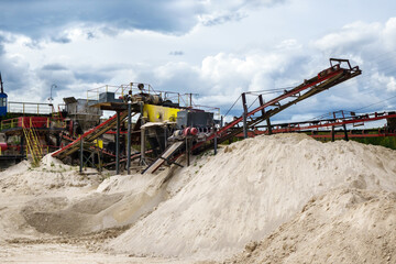 Stone crusher with its conveyors in opencast mine. Second one is on background. Also there are dumps of processed minerals