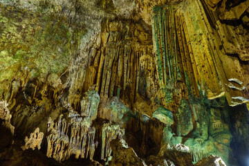 Stalactites hanging down from ceiling inside karst cave Astim or Asthma, Kizkalesi, Turkey. Their structure formed by falling water drops & small limestone particles during many centuries