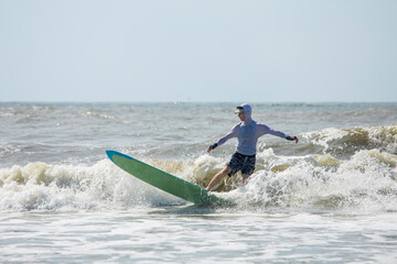 Middle aged man surfing a long board on the Atlatic Ocean in South Carolina.