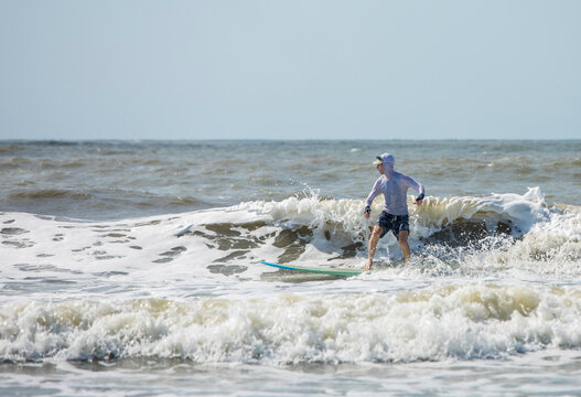Middle aged man surfing a long board on the Atlatic Ocean in South Carolina.