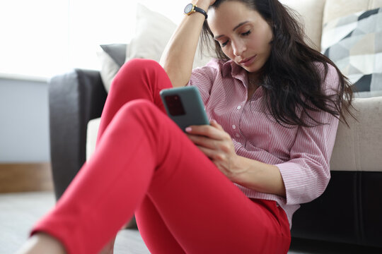 Sad woman sits on floor with closed eyes with smartphone in her hand. Signs of depression in women concept - Powered by Adobe