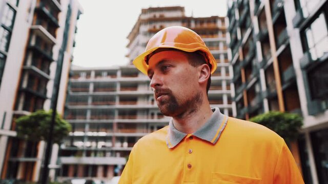 Construction site manager with expression of angry in orange uniform and helmet at construction site. Builder dissatisfied. Salary. Low wages. Hard work. Handyman. The foreman grumpy and quarrelsome