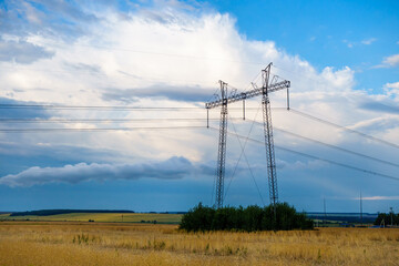 Tower of high voltage power line standing in countryside. Scenic sky is on background