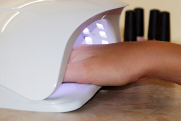female hand in a UV lamp for drying gel polish