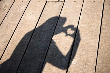 the shadow of the woman on the wooden floor hands forming love