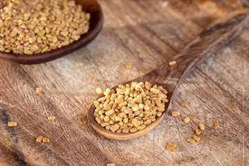 Fenugreek seeds on a wooden spoon