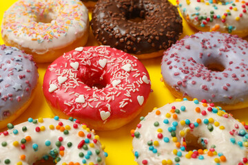 Flat lay with tasty donuts on yellow background