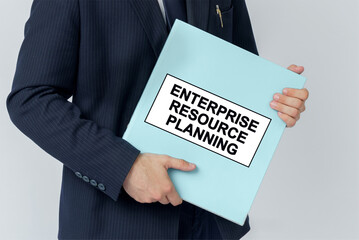 A businessman holds a folder with documents, the text on the folder is - ENTERPRISE RESOURCE PLANNING