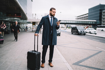 Confident businessman with luggage against airport