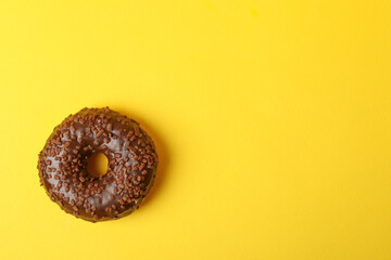 Tasty chocolate donut on yellow background, space for text