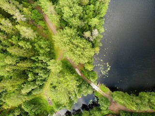 Lake in forest with cloudy sky. Aerial view Russian Karelia. wooden bridge path