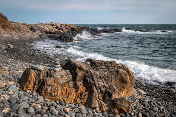 Maine's rocky coastline, highlighted by some stone stacking. - 376939933