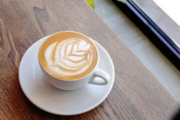 Cappuccino coffee leave shape of latte art on wooden table