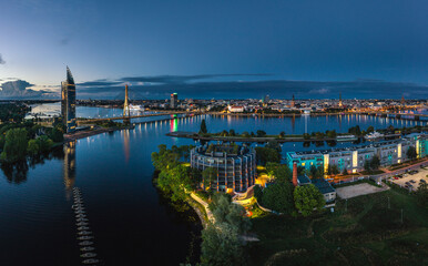 Fototapeta premium Riga city panorama with colorful sunset in the sky. Modern architecture meets old town. Picturesque view over riverside. 