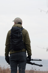 A photographer stands with his tripod overlooking an area for his next shot.