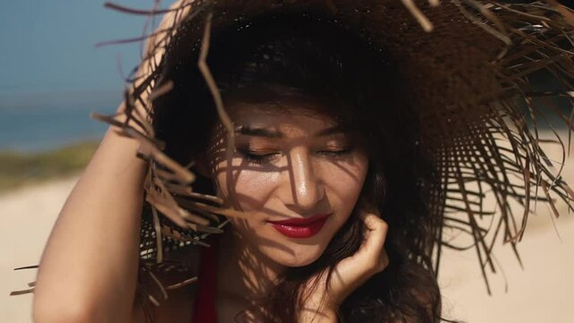Young mixed race woman with a straw hat and in red dress in hot summer day during vacation. Luxury sensual asian girl portrait smiling straight to camera. Beauty, travel, holidays, fashion lifestyle.
