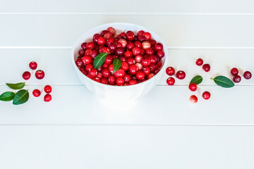 ripe cranberries in a white bowl on a white background view above. background with cranberries. cranberries and leaves on the table.